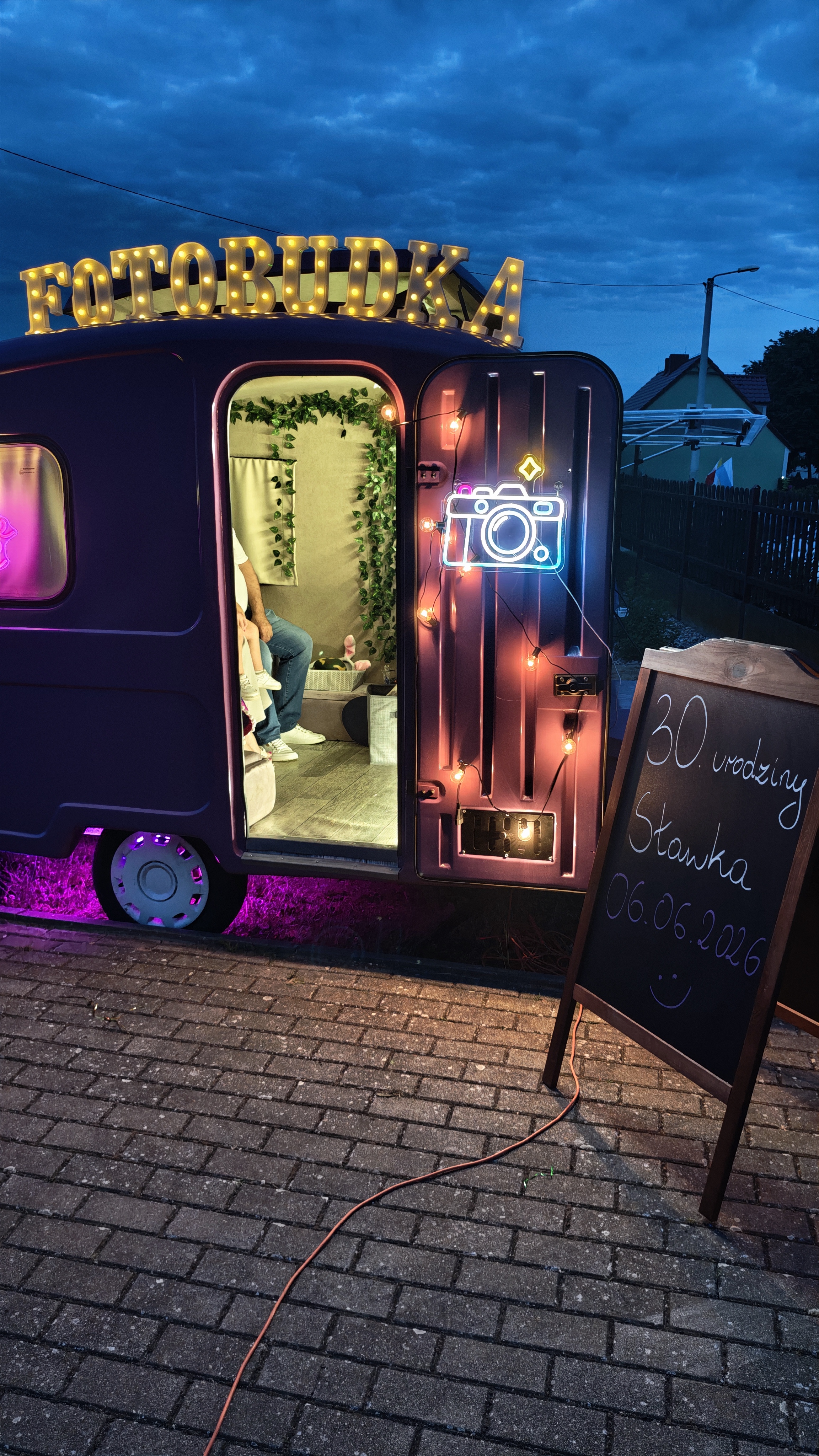 Fotofurka na 30. urodzinach – wnętrze fotoprzyczepy z dekoracją, neon aparatu i tabliczka z życzeniami